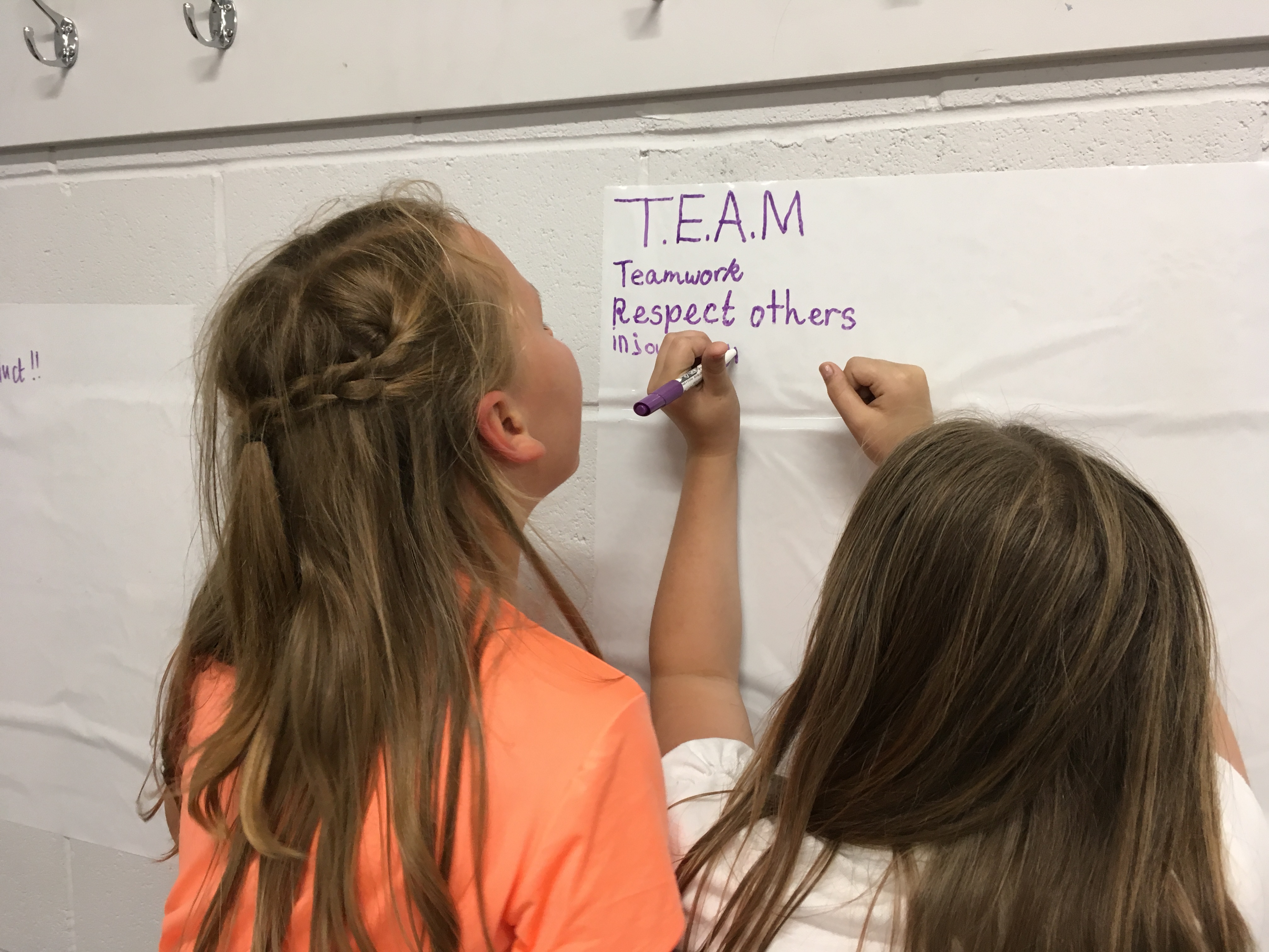 Two children write on a piece of paper