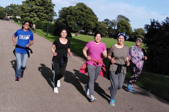 A group of women run together in the park.